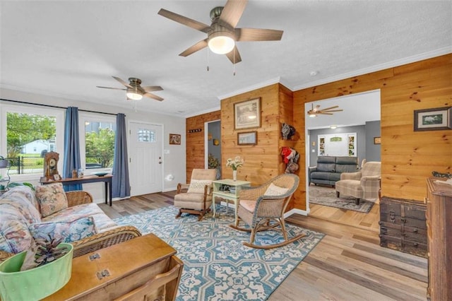 living room featuring wood walls, ornamental molding, and light hardwood / wood-style flooring