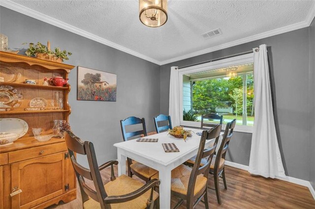 dining area with light hardwood / wood-style floors, a textured ceiling, and ornamental molding