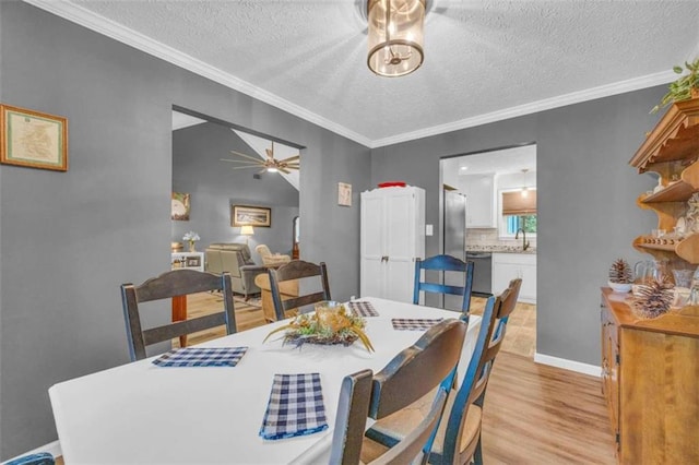 dining room featuring sink, crown molding, ceiling fan, a textured ceiling, and light hardwood / wood-style floors