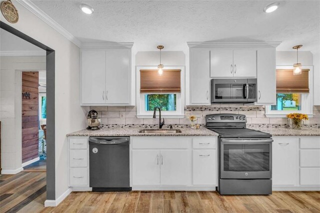 kitchen with white cabinets, sink, stainless steel appliances, and light hardwood / wood-style flooring