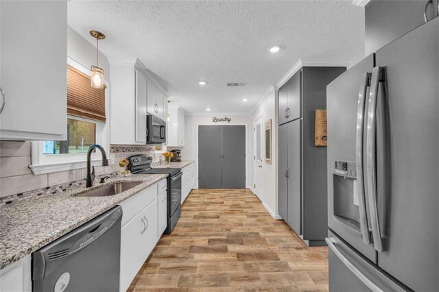 kitchen featuring white cabinetry, sink, decorative light fixtures, and appliances with stainless steel finishes