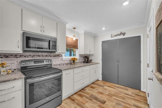 kitchen with stainless steel appliances, light hardwood / wood-style flooring, crown molding, decorative light fixtures, and white cabinets