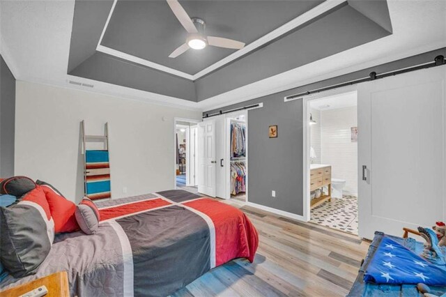 bedroom featuring connected bathroom, ceiling fan, a spacious closet, a barn door, and a closet