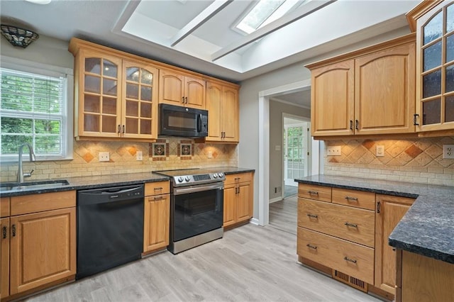 kitchen featuring tasteful backsplash, light wood-type flooring, a wealth of natural light, black appliances, and sink