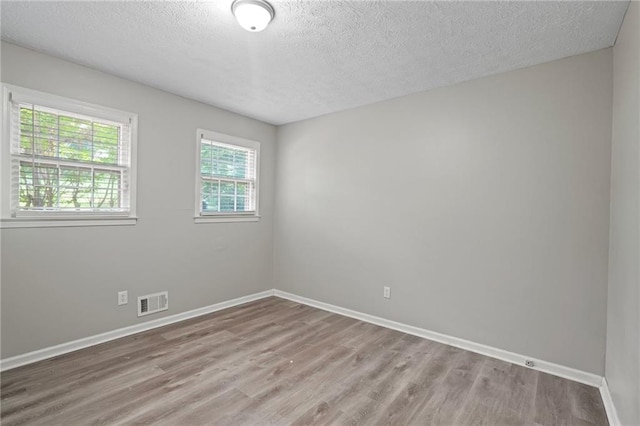 empty room with wood-type flooring and a textured ceiling