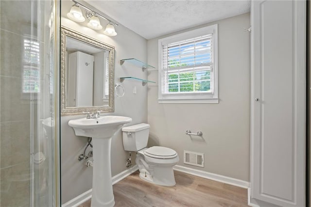 bathroom featuring a textured ceiling, hardwood / wood-style flooring, and toilet