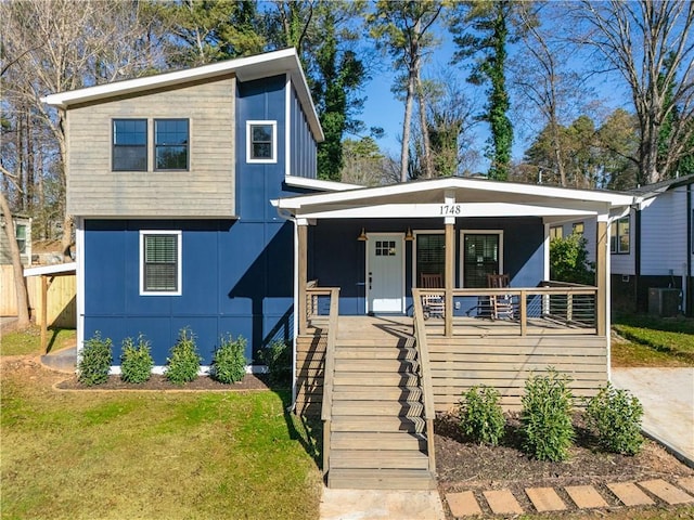 view of front of property with a porch, cooling unit, and a front lawn