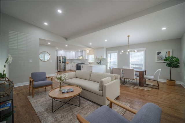 living room with a chandelier, wood-type flooring, and vaulted ceiling