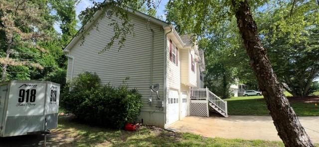 view of property exterior featuring an attached garage, driveway, and view of scattered trees