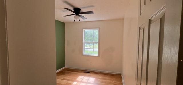 spare room with baseboards, wood finished floors, and ceiling fan