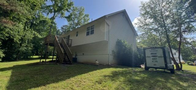 view of property exterior featuring stairs, a lawn, and a wooden deck