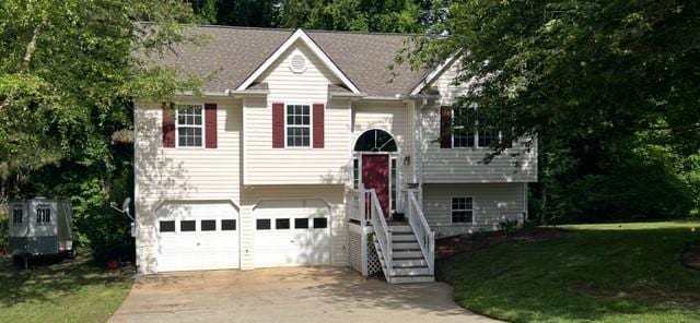 bi-level home featuring concrete driveway, a garage, and a front yard