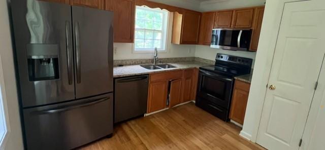 kitchen featuring stainless steel appliances, a sink, light wood-style flooring, light countertops, and brown cabinets