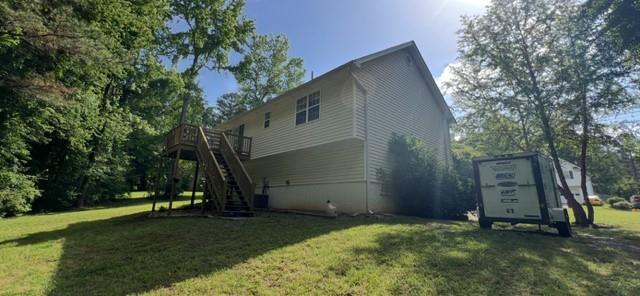 back of house featuring stairway, a lawn, and a wooden deck