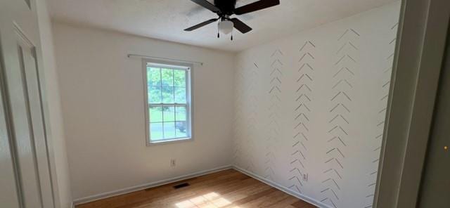 empty room with plenty of natural light, light wood-style floors, ceiling fan, and baseboards
