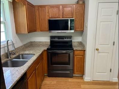 279 Fairview Dr, Dallas, GA 30157 - kitchen with electric range, a sink, brown cabinetry, light wood-style floors, and light stone counters