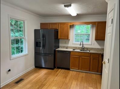 279 Fairview Dr, Dallas, GA 30157 - kitchen with black fridge, dishwasher, a sink, brown cabinets, and crown molding