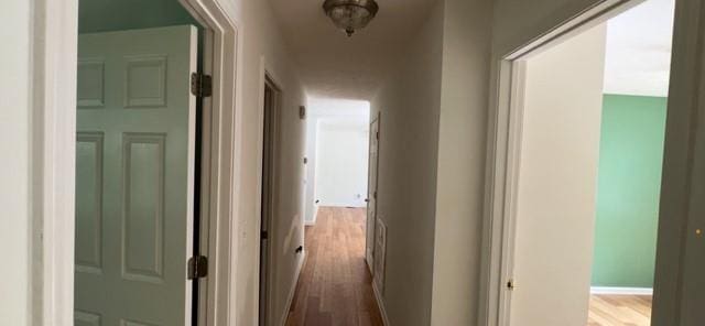 corridor with wood finished floors and baseboards