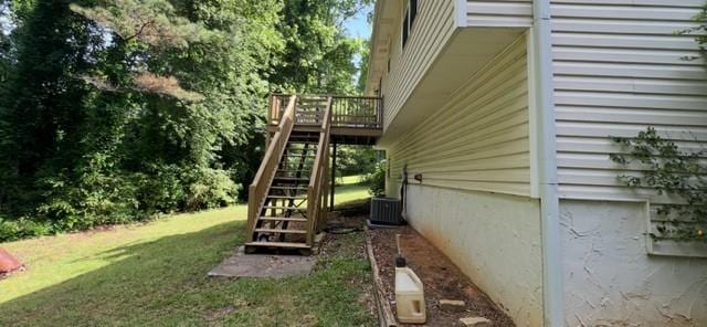 view of green lawn with stairway, a wooden deck, and central AC unit
