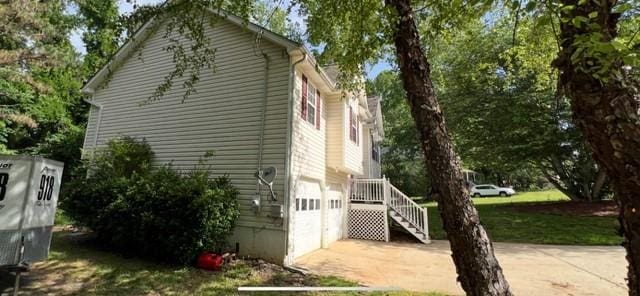 view of side of property with concrete driveway and a garage