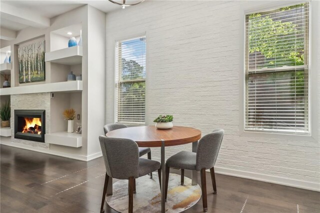 823 Canterbury Overlook, Atlanta, GA 30324 - dining room with brick wall, baseboards, dark wood-style floors, and a warm lit fireplace