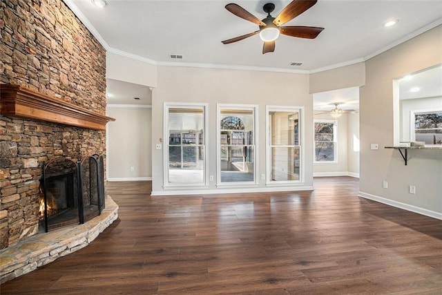 unfurnished living room with ceiling fan, dark hardwood / wood-style floors, a stone fireplace, and ornamental molding