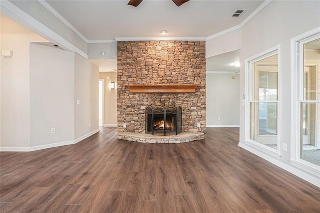 unfurnished living room featuring ceiling fan, ornamental molding, dark hardwood / wood-style flooring, and a stone fireplace