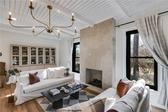 living room featuring wood ceiling, an inviting chandelier, light hardwood / wood-style flooring, beamed ceiling, and a premium fireplace