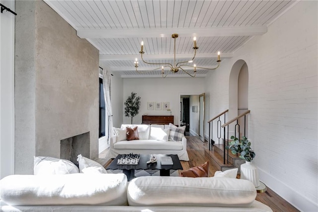 living room with beam ceiling, wood-type flooring, and a chandelier