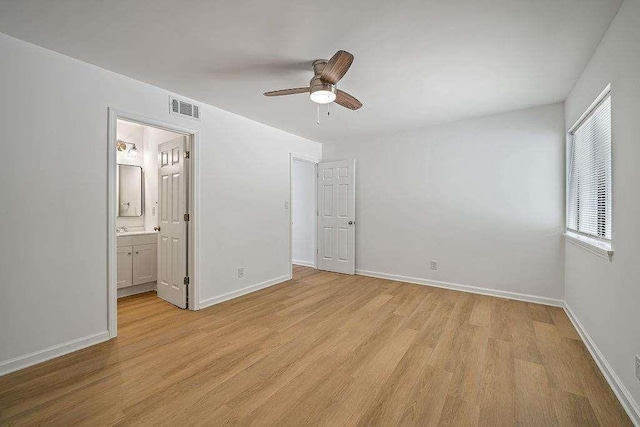 unfurnished bedroom with light wood-style flooring, connected bathroom, visible vents, and baseboards