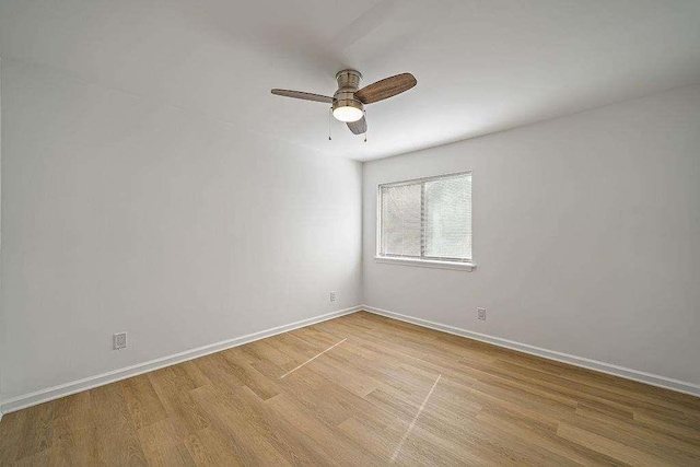 empty room with a ceiling fan, light wood-type flooring, and baseboards