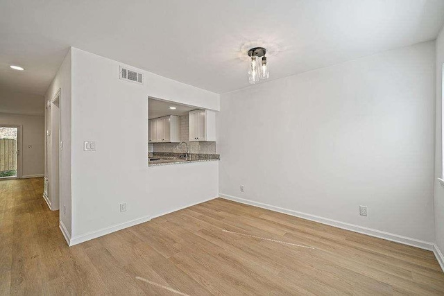 interior space featuring a sink, wood finished floors, visible vents, and baseboards