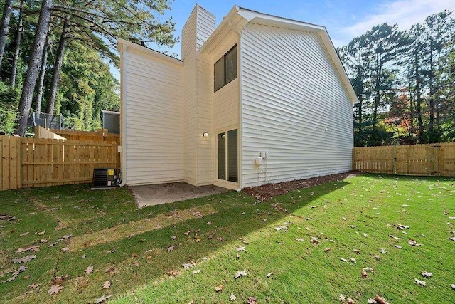 back of property featuring central AC unit, fence, and a yard