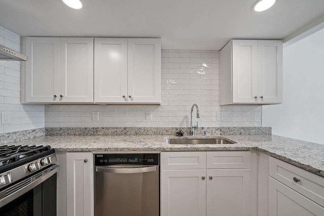 kitchen featuring appliances with stainless steel finishes, white cabinetry, a sink, and tasteful backsplash