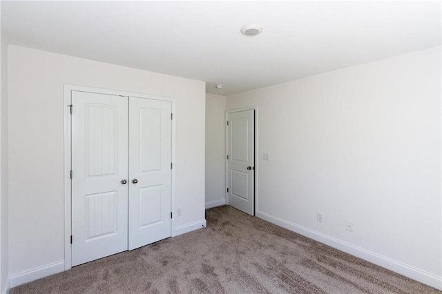 unfurnished bedroom featuring light carpet and a closet