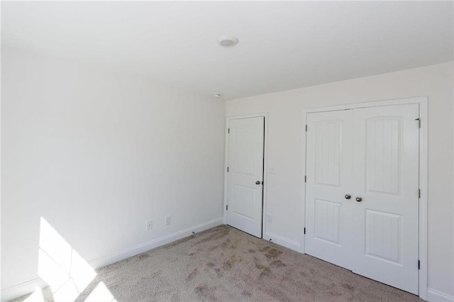 unfurnished bedroom with light colored carpet and a closet