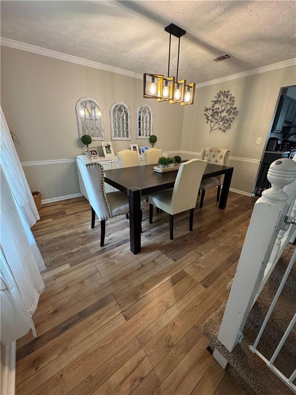 190 Grayland Creek Dr, Lawrenceville, GA 30046 - dining room featuring a textured ceiling, hardwood / wood-style flooring, crown molding, a chandelier, and baseboards