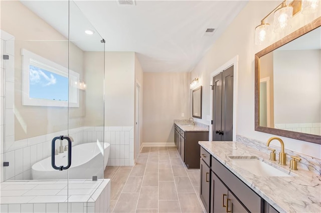 bathroom featuring vanity, a relaxing tiled tub, and tile patterned floors