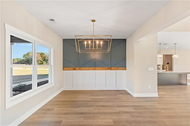 unfurnished dining area featuring hardwood / wood-style floors, a notable chandelier, and sink