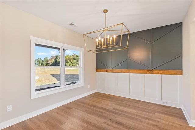 unfurnished dining area featuring wood-type flooring and a chandelier