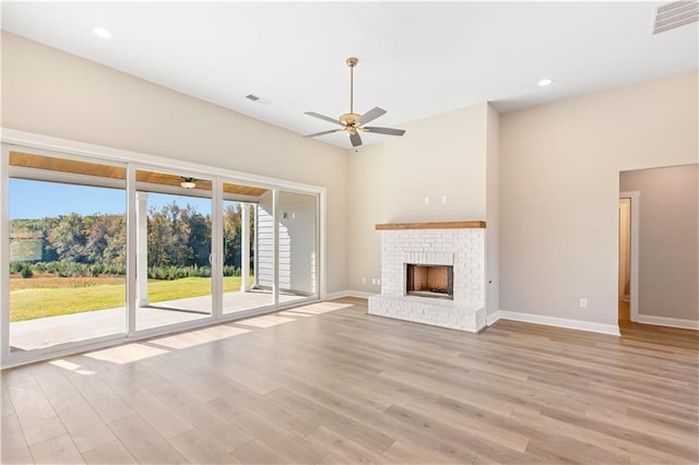 unfurnished living room with ceiling fan, light hardwood / wood-style floors, and a brick fireplace