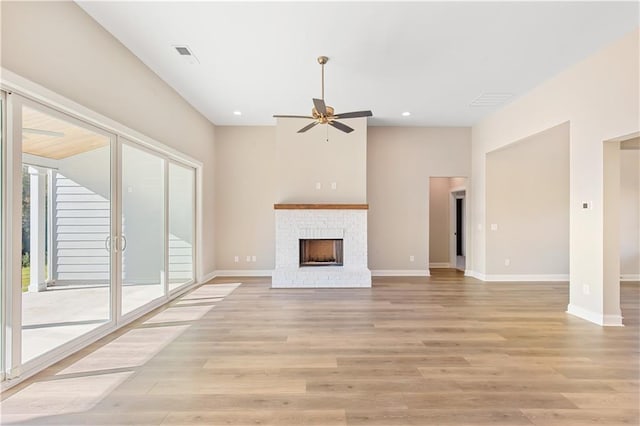 unfurnished living room with a brick fireplace, ceiling fan, and light hardwood / wood-style flooring