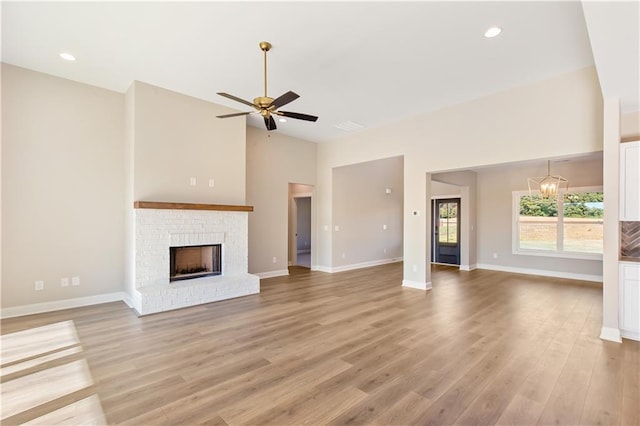 unfurnished living room with a fireplace, light hardwood / wood-style floors, and ceiling fan with notable chandelier