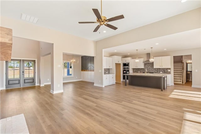 unfurnished living room featuring ceiling fan with notable chandelier, light hardwood / wood-style floors, and sink