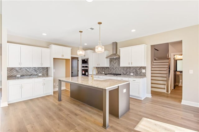 kitchen with white cabinets, sink, wall chimney exhaust hood, and stainless steel appliances