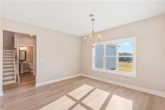 unfurnished dining area featuring a chandelier and light hardwood / wood-style floors