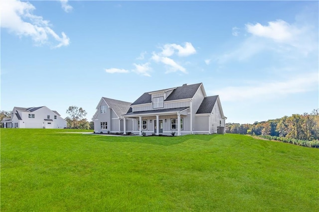 rear view of property with a yard, cooling unit, and covered porch