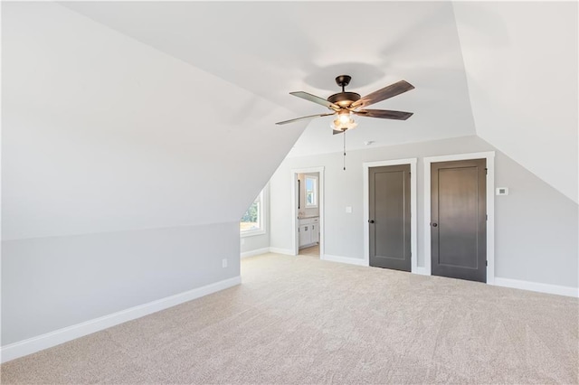 additional living space with ceiling fan, light colored carpet, and vaulted ceiling