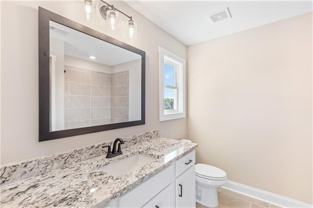 bathroom with tile patterned flooring, vanity, tiled shower, and toilet