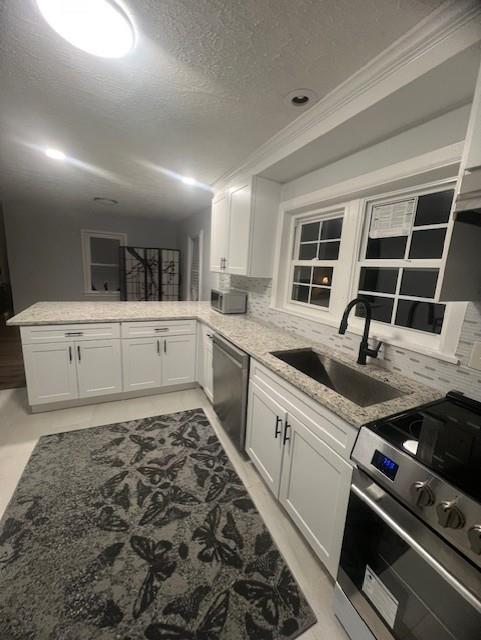 kitchen featuring stainless steel appliances, white cabinetry, sink, and kitchen peninsula